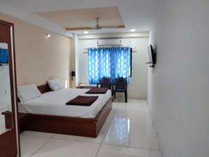 a bedroom with a bed and a chair and a window at Hotel Vraj in Rājpīpla