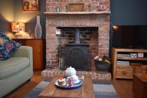 a living room with a brick fireplace with a coffee table at May's House in Rye Harbour