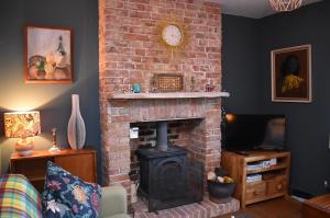 a living room with a brick fireplace with a clock at May's House in Rye Harbour
