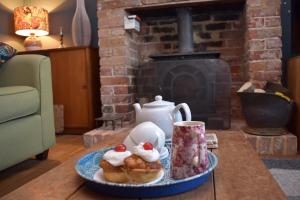 a plate of pastries on a table in a living room with a fireplace at May's House in Rye Harbour