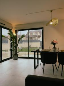 uma sala de jantar com uma mesa e uma grande janela em Maison moderne proche CDG, Paris em Tremblay En France