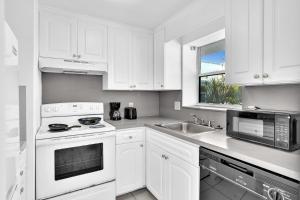 een witte keuken met witte kasten en een wastafel bij Coastal Sunset in Hollywood