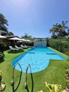 a swimming pool in a yard with grass at Ballena Rey Hotel in Uvita