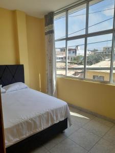 a bedroom with a bed and a large window at Departamento de Pablito Junto al Mar in Caleta Cruz