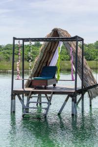 a hammock sitting on a pier in the water at Paraíso Nimah in Flores