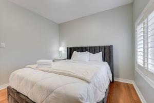 a white bedroom with a large bed with a wooden headboard at 4-BR Family Haven - Near Wonderland and Vaughan Mills in Vaughan