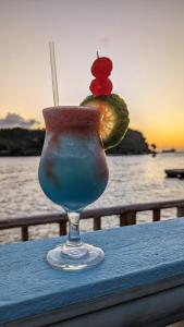 a drink sitting on top of a table with a sunset at Basil At Villa in Arnos Vale