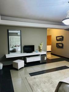 a living room with a tv and a mirror at TRMOTEL in Matola