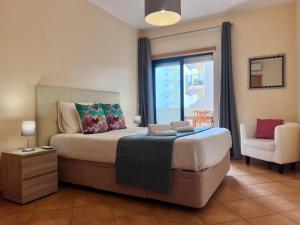 a bedroom with a bed and a chair and a window at Armação de Pêra Ocean Terrace With Pool by Homing in Armação de Pêra +37 photos