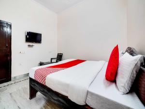 - une chambre avec un lit doté d'oreillers rouges et blancs dans l'établissement Shree Golju Palace, à Pantnagar