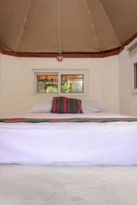 a large white bed in a room with two windows at Mayagloo in Flores