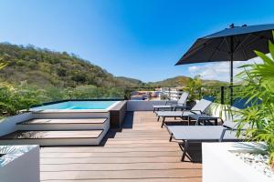 a deck with a pool and tables and an umbrella at 3018 - Ziba Condo 208 in Santa Cruz Huatulco