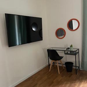 Un escritorio con una silla y un televisor en una pared. en Bausan44, en Nápoles