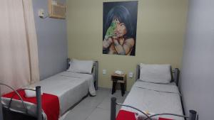 a room with two beds and a painting on the wall at Pousada Das Camelias in Volta Redonda