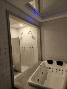 a bathroom with a bath tub and a mirror at Status Motel PE15 (Adults Only) in Olinda