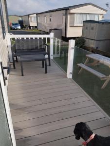 a black dog standing on a wooden deck at Mawson Retreat Dog Friendly Static Caravan in Millom