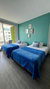 two beds in a room with blue walls at Cerca al Hotel Americas Ctgna Spiaggia Morros Piscina playa in Cartagena de Indias