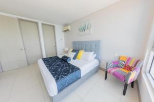 een slaapkamer met een bed en een stoel bij Edificio Palmetto Beach Apto 1702 in Cartagena