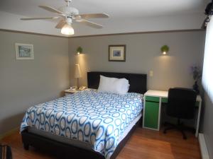 a bedroom with a bed and a desk and a ceiling fan at Motel Normandie in Louiseville