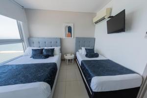 Habitación pequeña con 2 camas y TV. en Edificio Palmetto Beach Apto 1702, en Cartagena de Indias