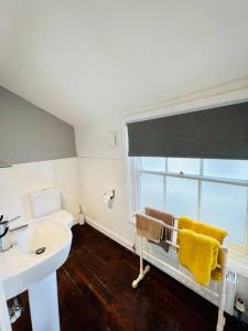 een witte badkamer met een wastafel en een raam bij Characterful & cosy cottage with large double room in Manningtree