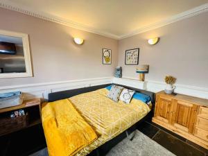 ein Schlafzimmer mit einem Bett mit einer gelben Decke in der Unterkunft Characterful & cosy cottage with large double room in Manningtree