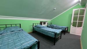 two beds in a room with green walls at Mexx Hostel in Baku