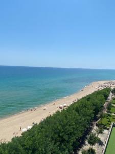 a beach with people and umbrellas and the ocean at Private Apartments in Yoo Bulgaria Complex in Obzor
