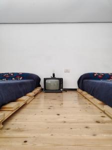 ナポリにあるMagma Home - Rooms & Roofのベッド2台とテレビが備わる客室です。