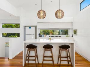 una cocina con una gran isla blanca con 2 taburetes en Soho Beach House - Apollo Bay, en Apollo Bay