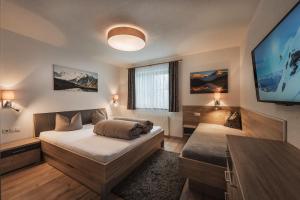 a bedroom with two beds and a flat screen tv at Alp Chalet Appartement in Kappl