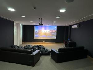 uma sala de estar com dois sofás pretos e um grande ecrã em Suíte Vista Azul - Frente para Pedra Azul em Pedra Azul