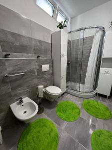 uma casa de banho com WC, lavatório e tapetes verdes em Apartman Centar em Tribunj