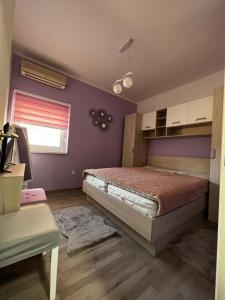 um quarto com uma cama e uma parede roxa em Apartman Centar em Tribunj