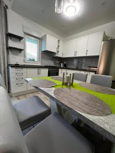 a kitchen with two tables and white cabinets at Apartman Centar in Tribunj