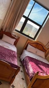two beds in a room with a large window at HOTEL NOSTRESS in Khenifra