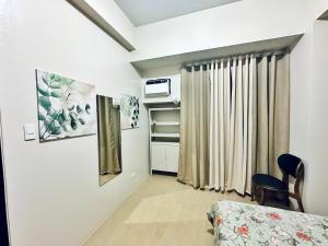 Cette chambre comprend un lit, une chaise et une fenêtre. dans l'établissement Rewind Spot Serene Apartment, à Manille