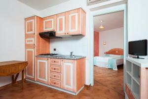 uma cozinha com um lavatório e uma televisão num quarto em S'Incantu Resort em Villasimius