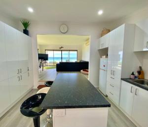 cocina con armarios blancos y encimera negra en Seaspray Beach House - Pet Friendly - 50m to Beach, en Apollo Bay
