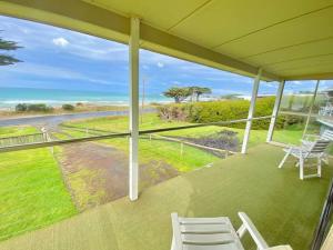 porche con sillas blancas y vistas al océano en Seaspray Beach House - Pet Friendly - 50m to Beach, en Apollo Bay