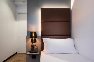 a bed with a brown headboard and a night stand with a phone at London Hotel in Milan