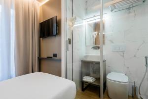 a bathroom with a bed and a toilet and a sink at London Hotel in Milan