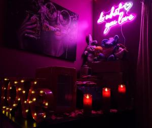 una camera oscura con un'insegna al neon e candele di Love Room Amour Glamour Lib proche gare rer 5 minute à pied ad Aulnay-sous-Bois