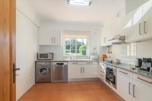 a kitchen with white cabinets and a washer and dryer at Vilamoura - VILLA VINTE in Vilamoura