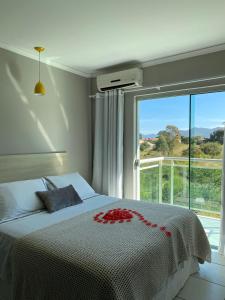 a bedroom with a bed and a large window at Hotel Pousada Laguna Rosa in Barra de Ibiraquera