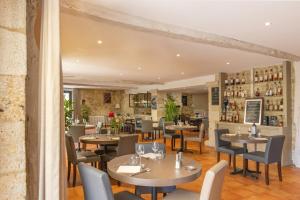 a restaurant with tables and chairs and a bar at Logis Hôtel La Ferme de Flaran in Maignaut