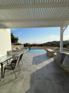 een patio met een tafel en stoelen en een zwembad bij Eleon Luxury Villa in Karpathos
