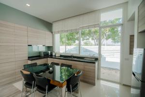 a kitchen with a glass table and chairs at City Beach Cha-am Pool Villa in Cha Am