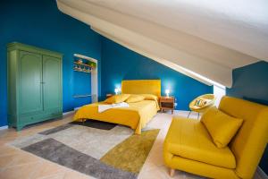 um quarto com paredes azuis, uma cama amarela e uma cadeira em Giolitti 39 - Moderna Mansarda nel cuore di Torino em Turim