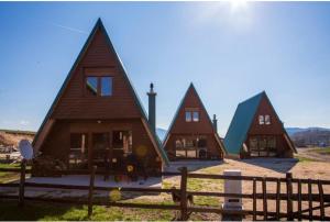 a group of cottages with pointed roofs in a field at Three Houses in Žabljak